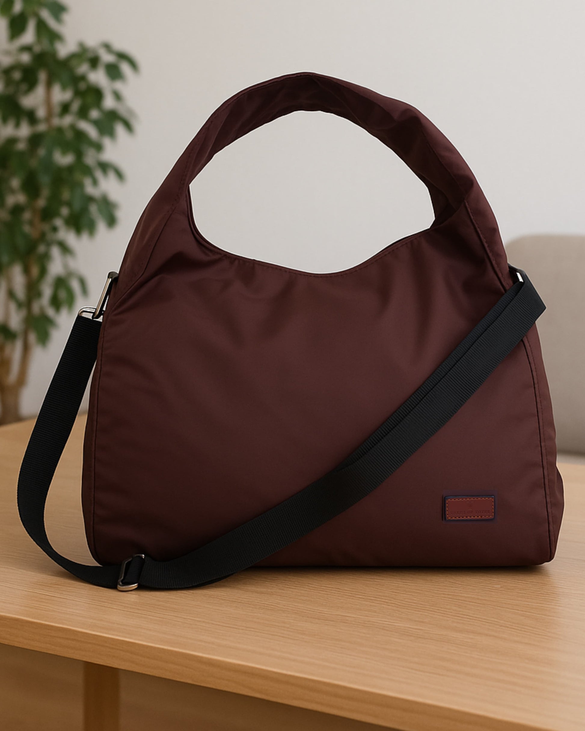 Minimalist black tote bag with a padded top handle, detachable crossbody strap, and front zipper pocket – made from water-resistant fabric for everyday functionality. Lightweight yet spacious, ideal for travel, office, gym, or casual use. A sleek and versatile design by Tales of Totes, offering modern utility and elevated style for Indian shoppers."